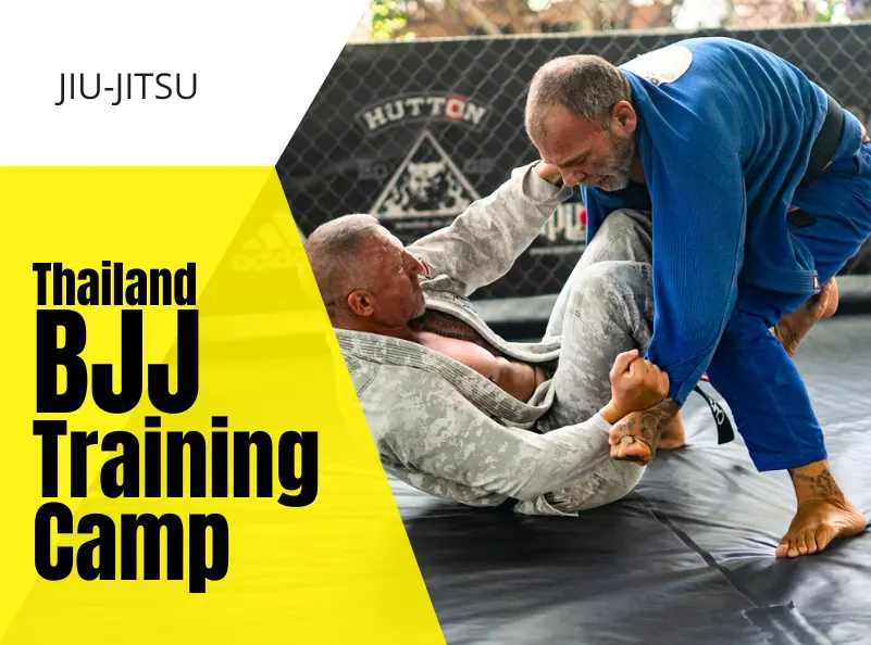 Two black belts in BJJ gis engage in a Brazilian Jiu-Jitsu sparring session on the mats at a training camp in Thailand. The scene captures the intensity and focus of their training, with the camp's logo visible in the background. The image highlights the dynamic and supportive environment of the Thailand BJJ Training Camp.