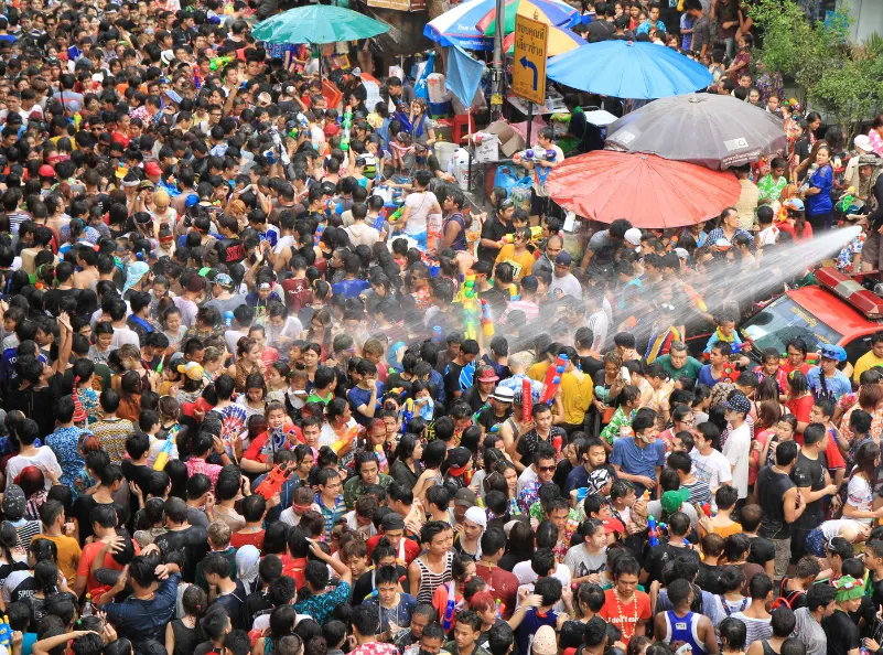 A large crowd celebrating Songkran in Thailand with water fights, colorful clothing, and festive energy, showcasing the vibrant atmosphere of the Thai New Year festival.