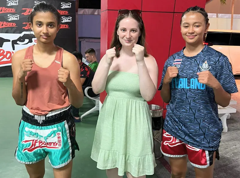 In this inspiring snapshot from Kombat Group, Julia (center) stands proudly with two skilled Thai boxers, embodying the spirit of empowerment and transformation. Julia, who came to Kombat Group to improve her fitness and martial arts skills, has made remarkable progress. This image captures the camaraderie and supportive environment that Kombat Group offers, allowing guests to thrive and connect with like-minded individuals. Join Julia in experiencing a journey of self-discovery and empowerment through martial arts and holistic wellness at Kombat Group.