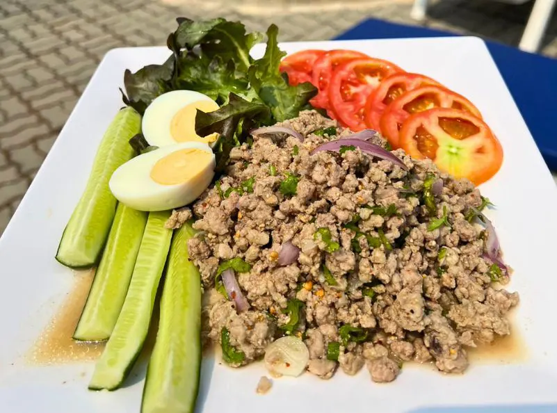 Traditional Thai larb salad with minced meat, fresh cucumber, boiled eggs, lettuce, and tomato slices, offering a protein-packed, healthy meal option at Kombat Group.