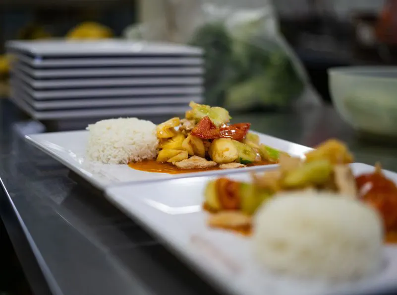 Freshly prepared sweet and sour Thai dish with rice served on a white plate, highlighting nutritious and balanced meals at Kombat Group.