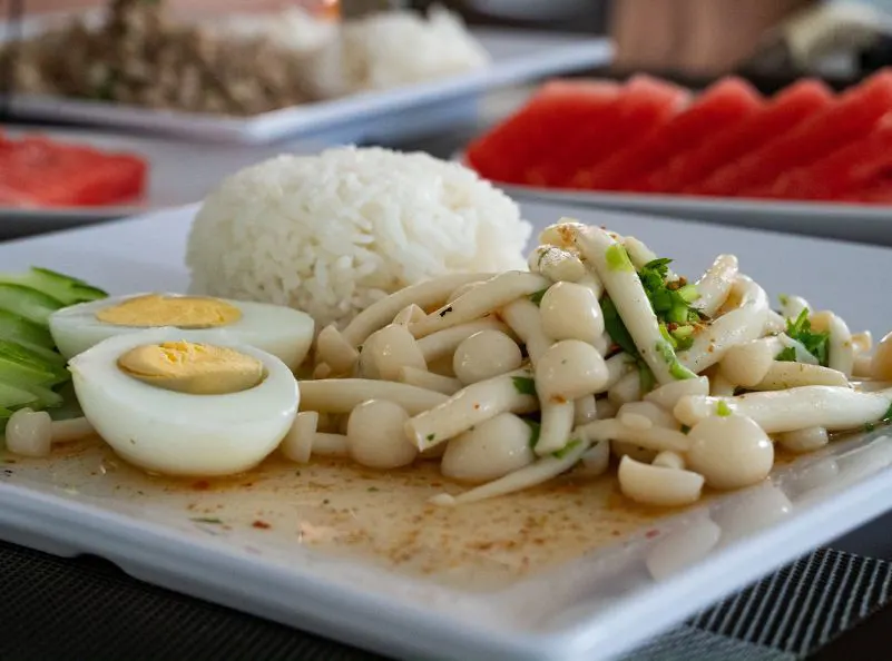 Healthy Thai dish featuring mushrooms, boiled eggs, rice, and cucumber slices, offering a balanced and nutritious meal option at Kombat Group.